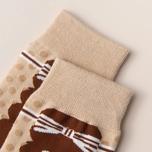 Close-up of beige knit socks with ribbed cuffs and brown bear pattern detail