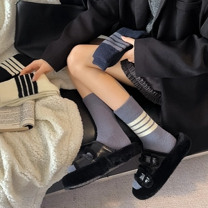 Detail of warm knitted crew socks with classic triple stripes in navy, grey, and cream