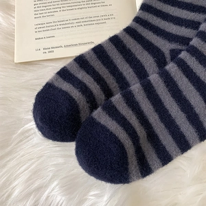 Close-up of blue and grey striped fuzzy socks on a soft plush white background