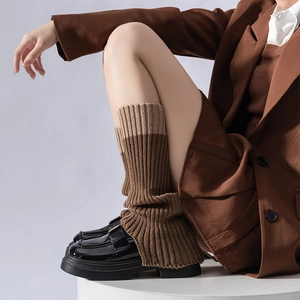 Dettaglio di scaldamuscoli in maglia a coste bicolore marrone con scarpe con zeppa
