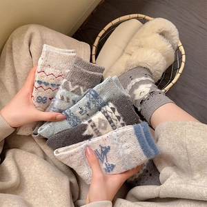 Detail von dicken Wollsocken mit nordischen Mustern und süßer Schafstickerei