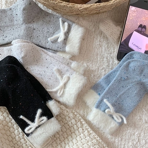 Detail of plush faux fur cuffs and delicate bowknots on speckled knit winter socks