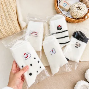Detailaufnahme von vier Paar warmen Wintersocken mit süßer Tierstickerei und Verpackung