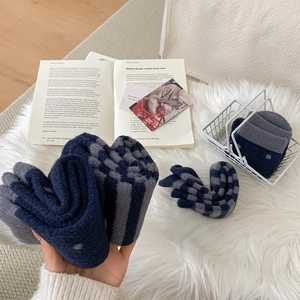 Detailed macro view of thick navy and grey striped plush socks on a soft white carpet
