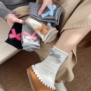 Detail of soft knit mid-calf socks featuring a cute 3D bow decoration for autumn