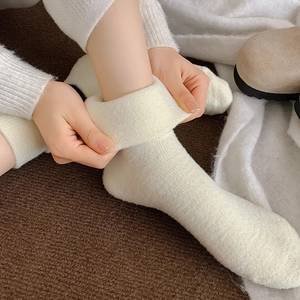 Detailed close-up of warm cream-white knitted crew socks with thick winter texture