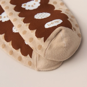 Close-up of knitted cotton socks with cute cartoon bear pattern and soft beige texture