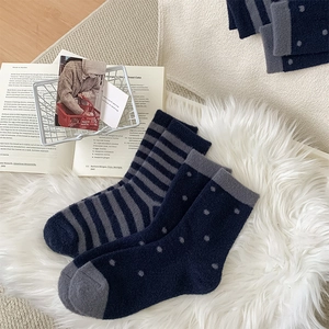 Close-up of thick plush striped socks on a soft white rug for cozy winter warmth