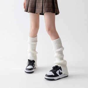 Detail of white chunky knit leg warmers showing the ribbed texture and soft fabric
