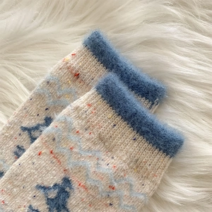 Detail von Wollsocken mit blauen Tiermustern und Plüschbündchen für Winterwärme
