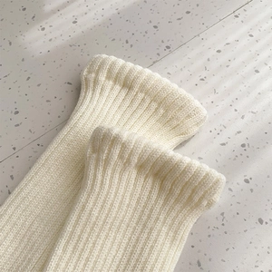 Close-up of cream white ribbed knit leg warmer showing thick texture and stitch details