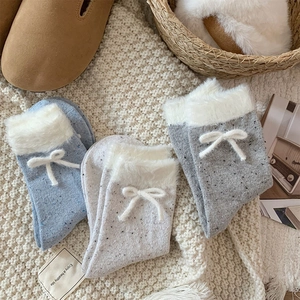 Close-up of knit winter socks with plush faux fur trim and bow detail in three colors