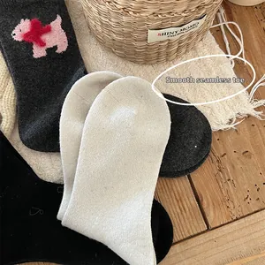 Detail of flat seamless toe stitching on beige and black wool socks with dog pattern
