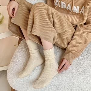 Close-up of cream wool knit socks with vertical stripes and ruffled cuffs for winter warmth