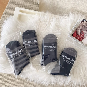Four pairs of thick striped and polka dot plush socks in separate zipper bags on a rug