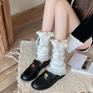 Lace ruffle leg warmers with satin bows paired with black loafers in a cozy setting
