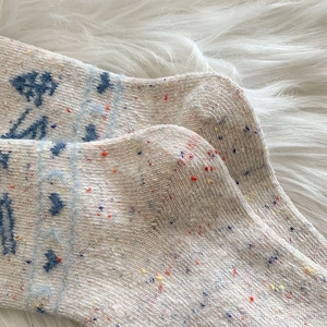 Nahaufnahme dicker Wollsocken mit blauen Herzmustern und strukturierter Strickferse