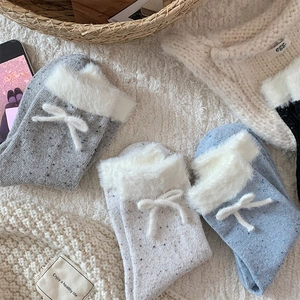 Detailed view of winter knit socks with faux fur trim and cute ribbon bows in mixed colors