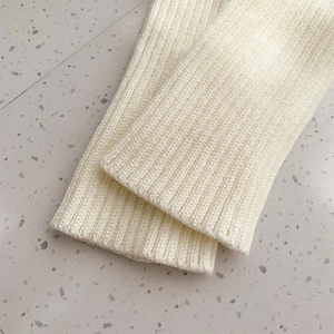Detailed macro view of the thick vertical ribbed knitting texture on cream leg warmers