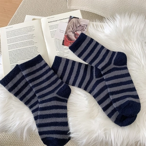Detail of soft striped plush socks on a cozy rug with a book for winter comfort