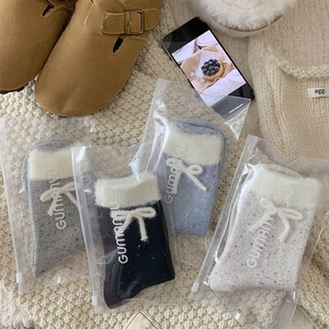 Detailed view of four winter socks with faux fur trim and cute bows in retail bags