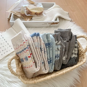 Korb mit dicken Strick-Wollsocken mit Vintage-Mustern in gemütlicher Winterszenerie
