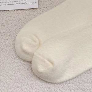 Close-up of thick beige plush socks with soft texture and flat toe seams for winter