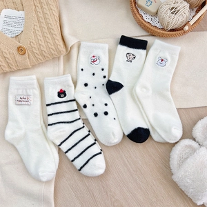 Five pairs of fluffy thermal socks with cute animal embroidery on a warm wooden floor
