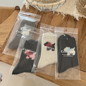 Detail of wool socks with cartoon dog and bow motifs in premium zipper packaging