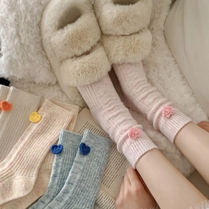 Gros plan sur des chaussettes en laine avec cœurs en crochet 3D aux couleurs pastel