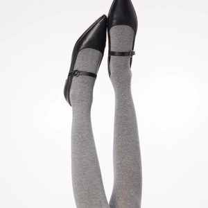 Close-up of gray knit over-the-knee socks paired with black pointed Mary Jane shoes