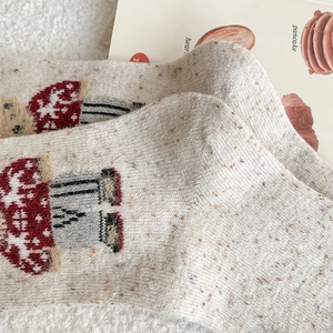 Close-up of knit wool socks featuring cute mushroom pattern and vintage speckled yarn texture