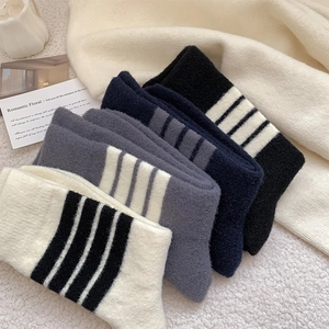Detail of five pairs of thick striped wool socks in various colors on cozy background