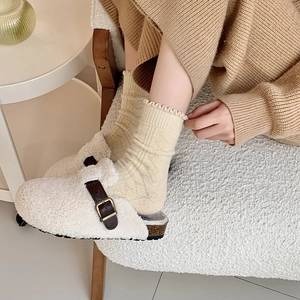 Close-up of light yellow knit wool socks paired with white fleece Boston style slippers