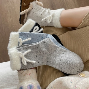 Detailed texture of warm knit socks with cute bows and fuzzy white faux fur trim cuffs