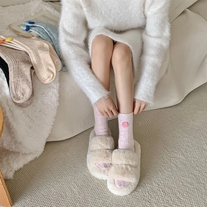 Détail de pantoufles en peluche crème et chaussettes en tricot de laine à motif cœur