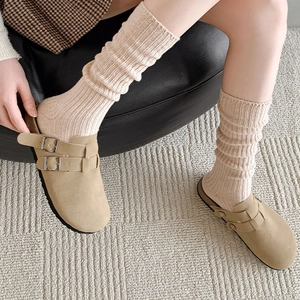 Detail of khaki suede mule clogs styled with cream knit slouchy leg warmer socks