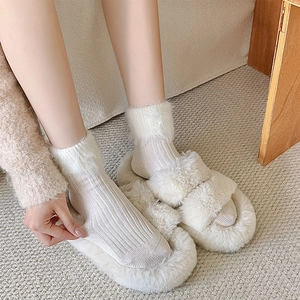 Close-up of cream knit socks with plush faux fur trim and matching fuzzy slippers
