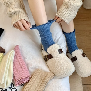 Close-up of cozy wool socks with ruffled edges and thick knitted texture in cream blue