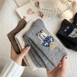 Detail of wool blend thermal socks featuring cartoon bear embroidery and speckled texture
