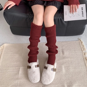 Deep red ribbed knit leg warmers paired with beige wool clogs in a cozy autumn style