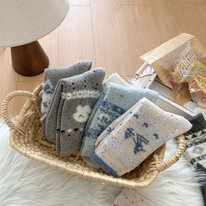 Dicke Wollsocken mit festlichen Mustern, ordentlich in einem rustikalen Korb präsentiert