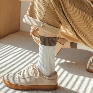 Close-up of ribbed wool socks with brown contrast cuffs paired with suede sneakers