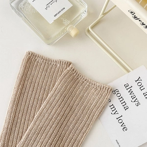 Close-up of beige knit leg warmers showing ribbed texture and thick material in a cozy setting