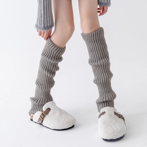 Detail of grey ribbed knit leg warmers paired with white plush buckle slippers