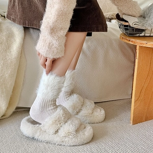 Detail of plush faux fur slippers and thick knit thermal socks in a cozy home setting
