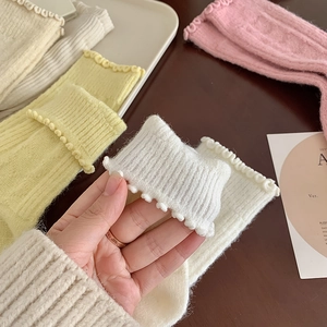 Close-up of ruffled cuff detail on thick knit wool socks in cream and pastel colors
