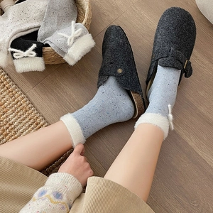 Detail of light blue polka dot socks with plush trim and bow decoration on feet
