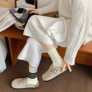 Detail of beige suede clog mules with cork footbed and striped warm wool socks