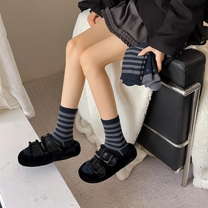Detail of striped thermal socks and black plush sandals on soft lamb wool blanket